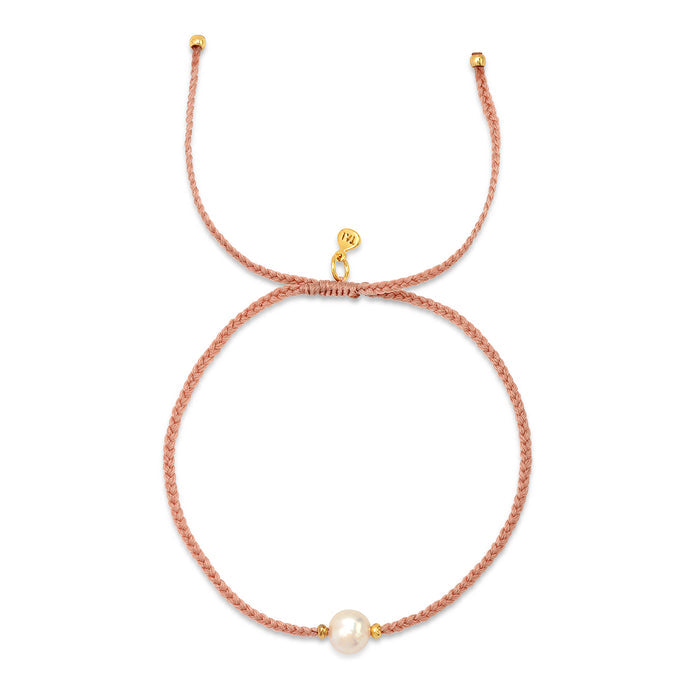 Pink beaded bracelet with gold charm and single white pearl accent