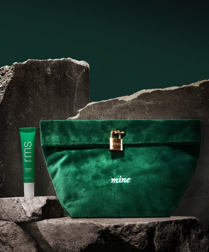 Velvet green pouch with a gold lock and the word "mine" embroidered, paired with a green RMS Beauty tube, presented on stone slabs for The Chameleon 2-Piece Set.
