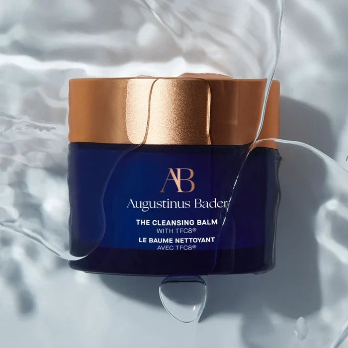 Augustinus Bader The Cleansing Balm jar with gold lid on watery background