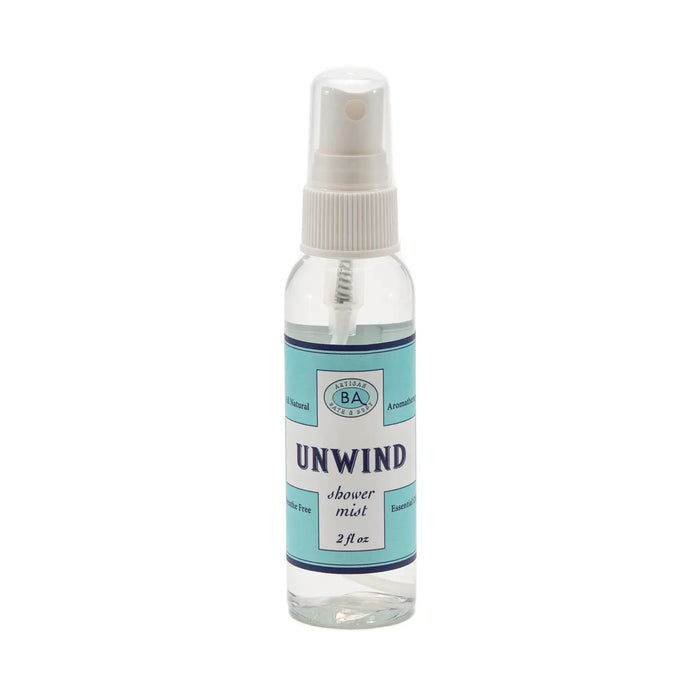 The "Unwind" collection by Baudelaire includes a large jar of aromatherapy bath salts, a soap bar, shower mist, and citrus roll-on. Presented in light blue and white packaging against decorative tiles.