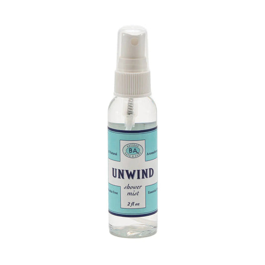 The "Unwind" collection by Baudelaire includes a large jar of aromatherapy bath salts, a soap bar, shower mist, and citrus roll-on. Presented in light blue and white packaging against decorative tiles.