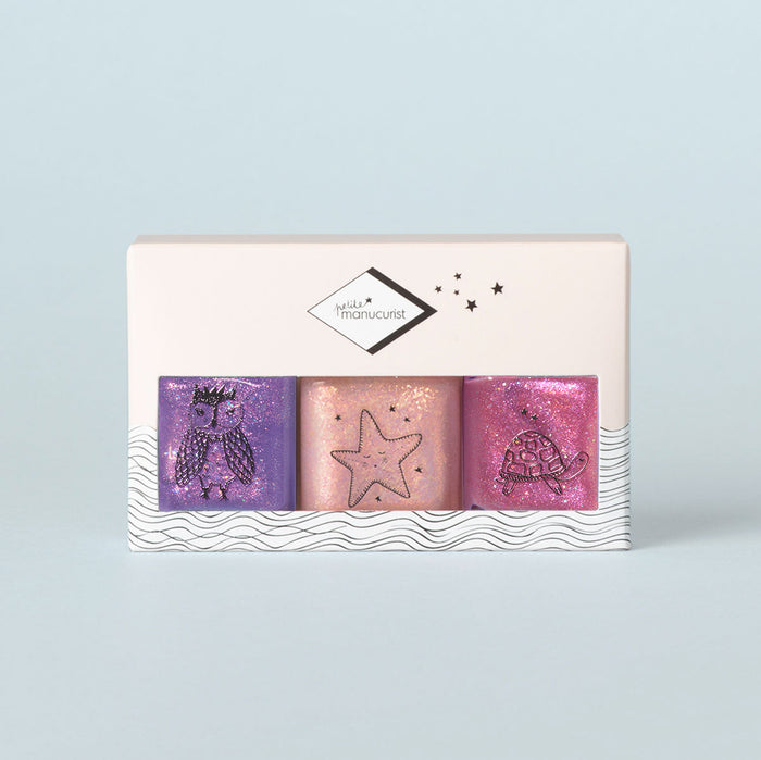 The Manucurist Betty Scarlett Stella Trio features three glittery, kid-safe, washable nail polishes in purple, peach, and pink with cute owl, starfish, and turtle designs. Packaged in a white box for creative fun!.