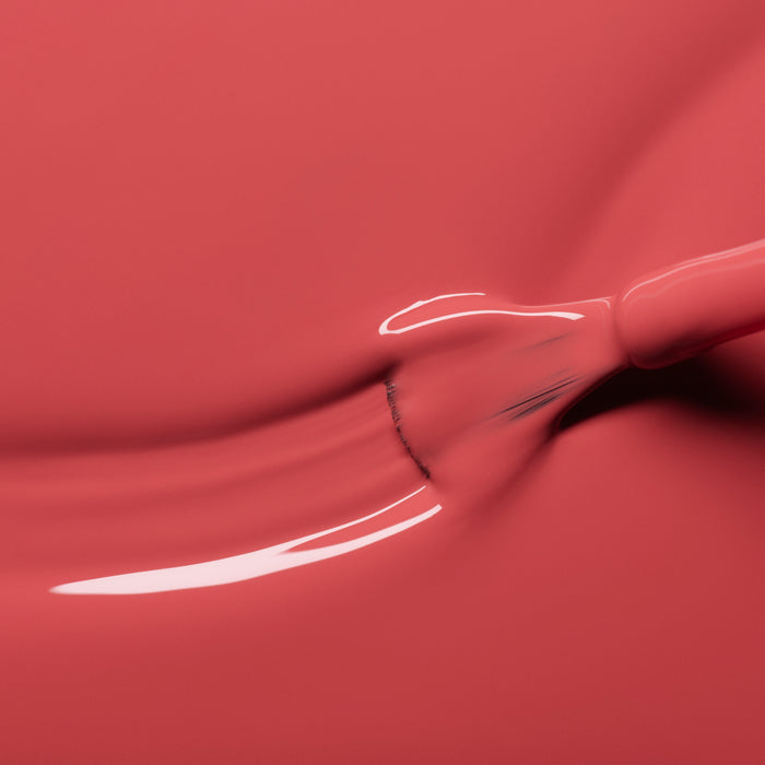 A close-up of a brush spreading glossy Bois de Rose nail polish from Manucurist, creating smooth, reflective rosewood pink streaks.