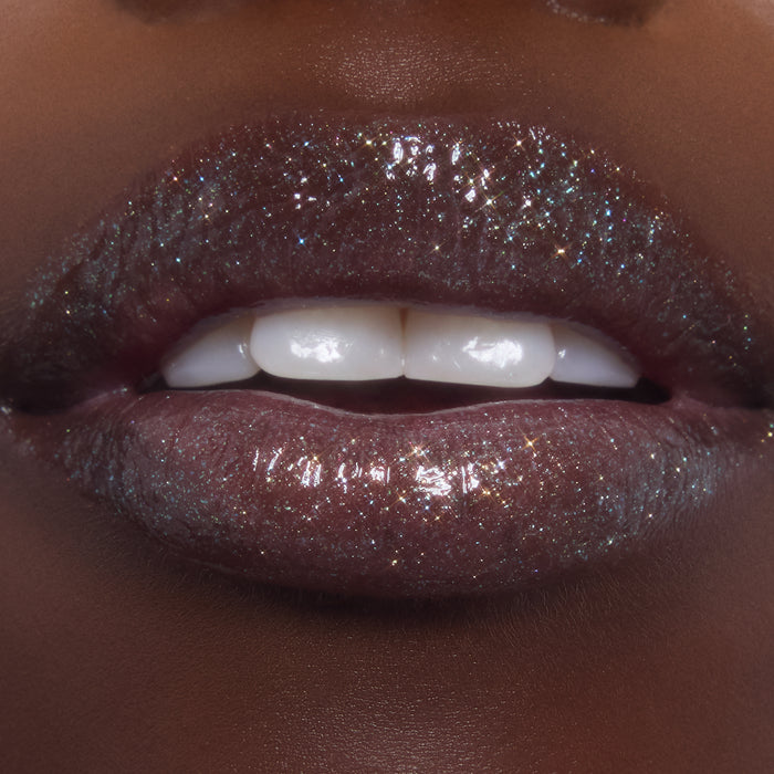 Shimmering lips wearing ColourPop Ultra Glossy Lip in Totally Swamped, a deep cool-toned gloss packed with multicolor sparkle, shown in an extreme close-up as the model parts their lips to reveal a high-shine, wet-look finish.