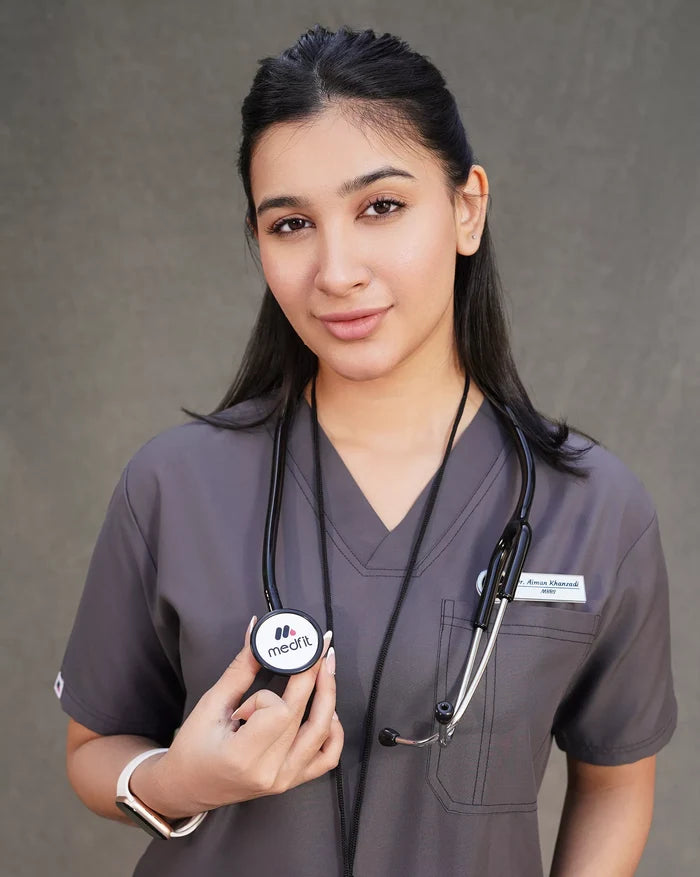 women doctor  in Medical scrubs in Pakistan with a stethoscope and personal device on a gray background