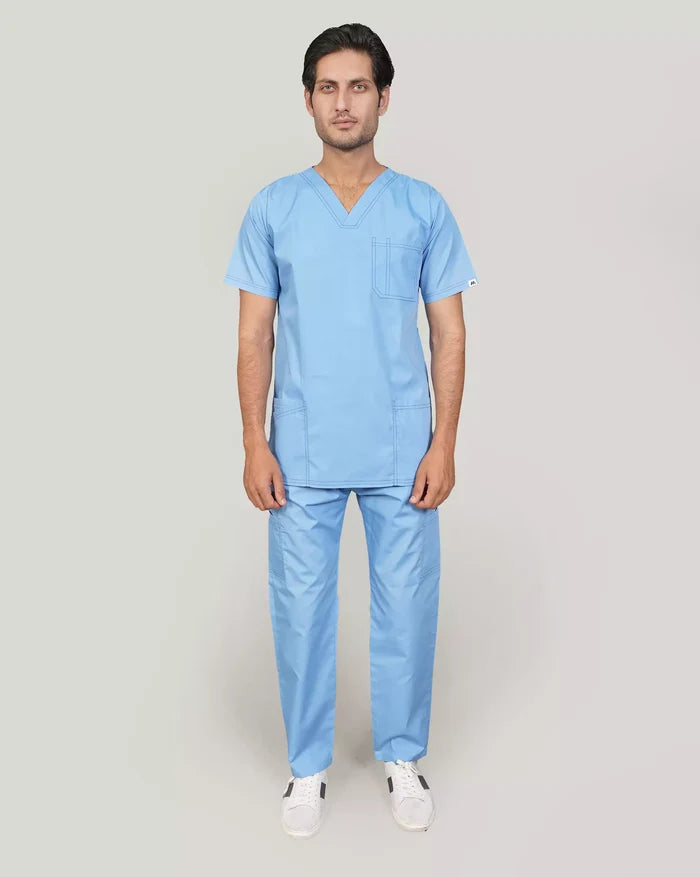 A doctor wearing a blue V-neckline scrub top with five pockets, Scrubs Karachi, and matching blue straight cargo trousers with additional pockets, standing against a plain background.