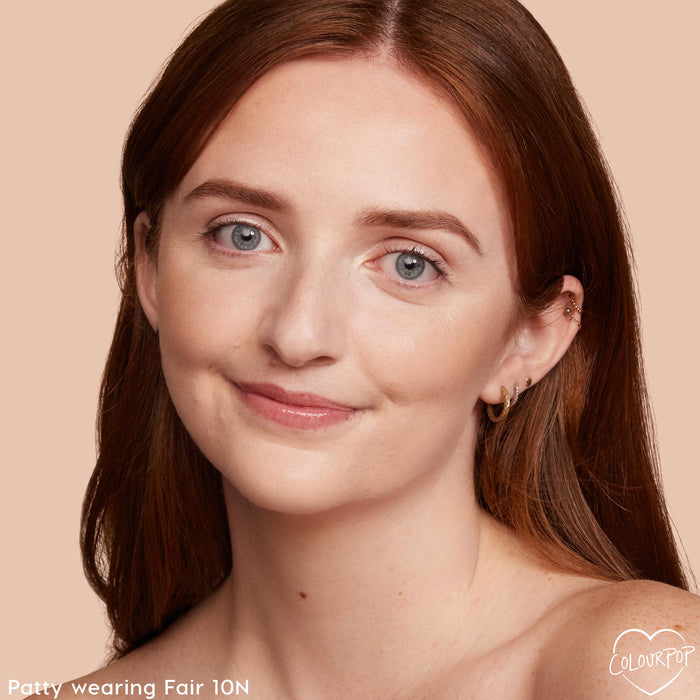 ColourPop Pretty Fresh Creamy Concealer in Fair 10 N brightening under eyes and evening skin tone on a smiling model; close-up portrait against a peach background shows light‑neutral coverage with a natural, satin finish.