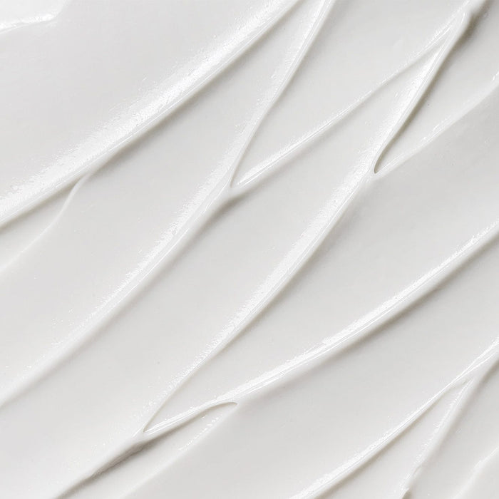 Close-up texture of smooth white cream with soft diagonal ridges and a glossy finish.