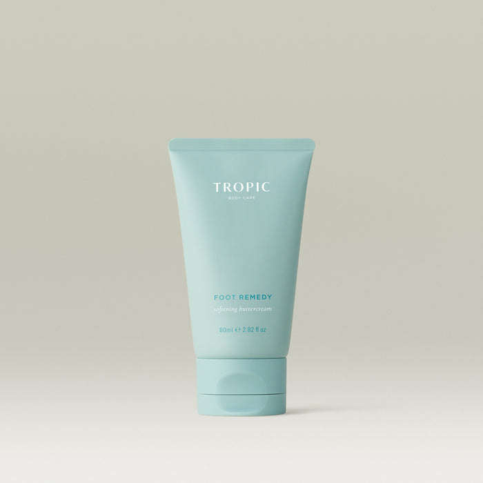 Tropic Foot Remedy softening buttercream in a blue tube on a neutral background.