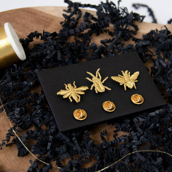 Golden embroidered brooch pins featuring three tiny bug designs, perfect for plant lovers and botanical-themed accessories.