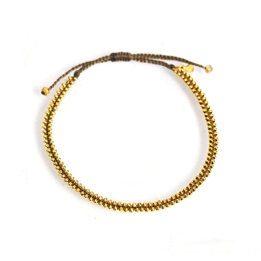 Beaded bracelet with gold bead accents on dark cord and small gold end caps
