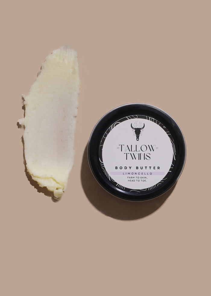 A tin of Limoncello Body Butter beside a thick swipe of pale yellow body butter.