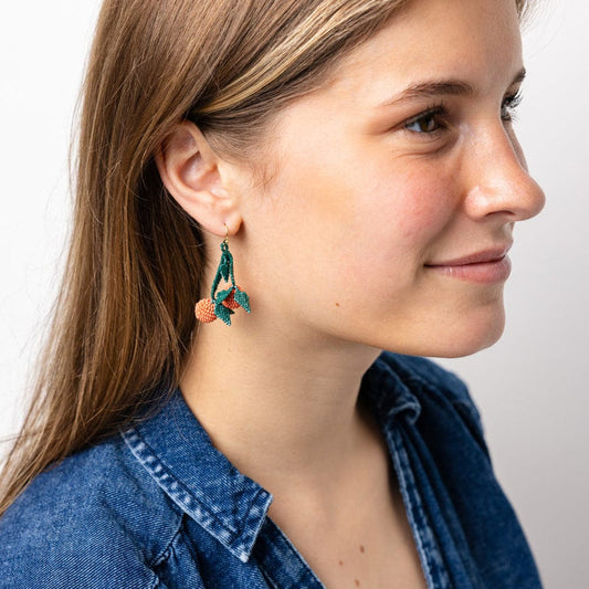 Beaded dangle earrings worn, green leaf shapes with orange bead accents