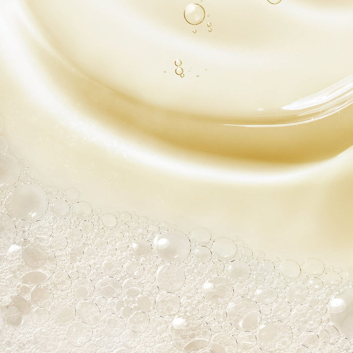 Close-up texture of Tropic Luxury Bath Foam, showing silky golden liquid with delicate, airy bubbles that create a rich, luxurious lather.