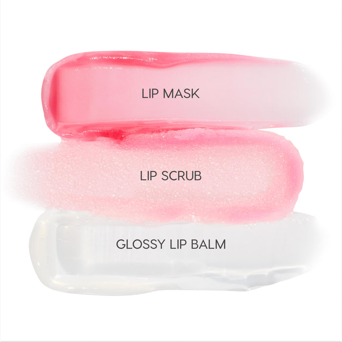 Mistletoe Kisses Lip Care Kit by Colourpop swatched on white: glossy pink lip mask, sugar-pink lip scrub, and clear glossy lip balm, shown in wide strokes to highlight texture and shine in this holiday set.
