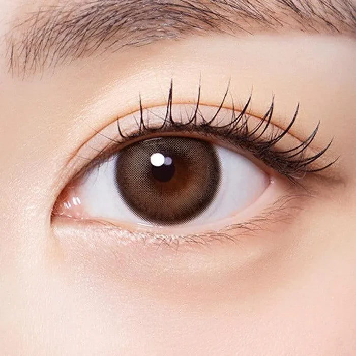 Macro shot of an eye wearing the Olola Muted Choco prescription colour contact lens, showing the multi-colored detail and natural effect on dark brown eyes.