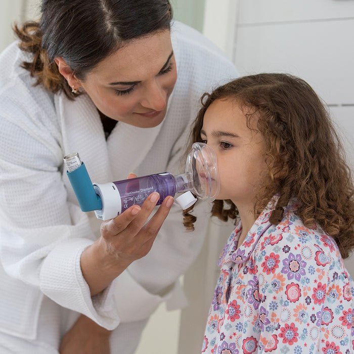 Woman assisting a young girl with an optichamber in a home setting