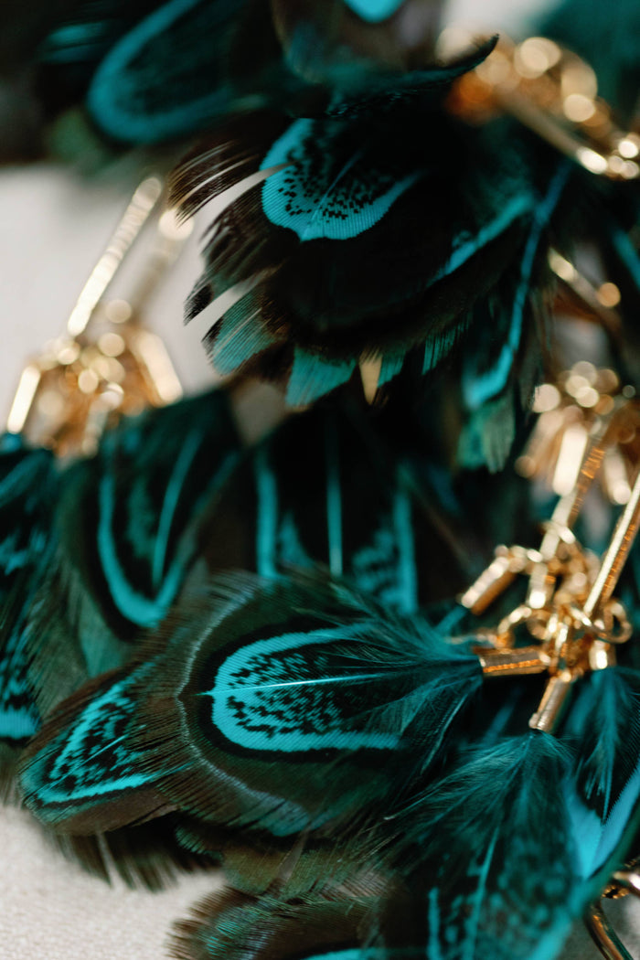 Peacock feather tassel earrings by St Armands Designs of Sarasota featuring vibrant feather and gold-tone details.