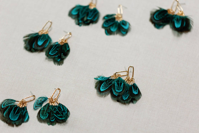 Peacock feather statement tassel earrings by St Armands Designs of Sarasota featuring vibrant feather and tassel details.