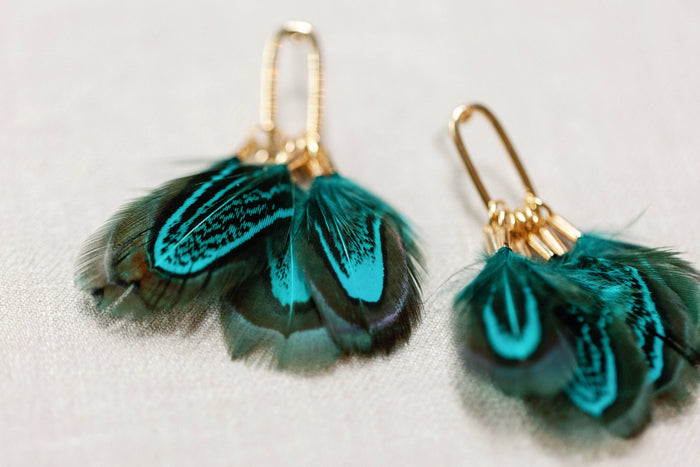 Peacock feather statement tassel earrings by St Armands Designs of Sarasota, featuring vibrant feather and tassel details.
