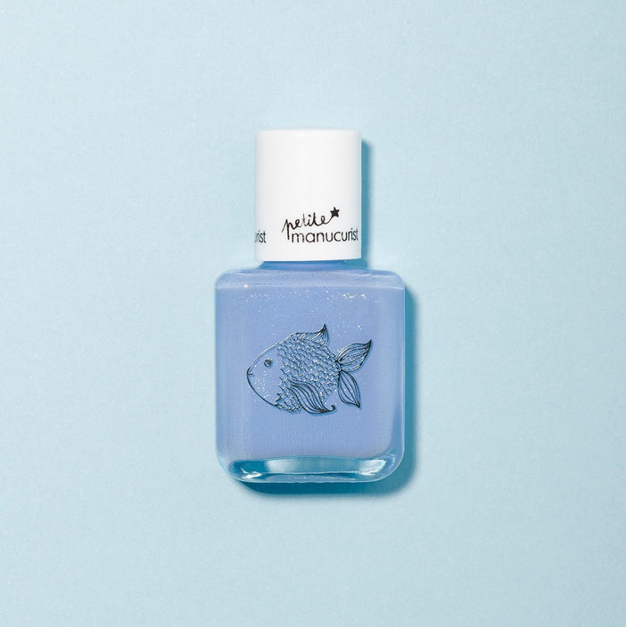 A bottle of Pomme the Fish light blue, non-toxic kids nail polish by Manucurist features a fish illustration and white cap, set against a pale blue background.