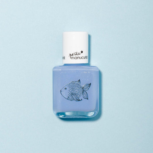 A bottle of Pomme the Fish light blue, non-toxic kids nail polish by Manucurist features a fish illustration and white cap, set against a pale blue background.