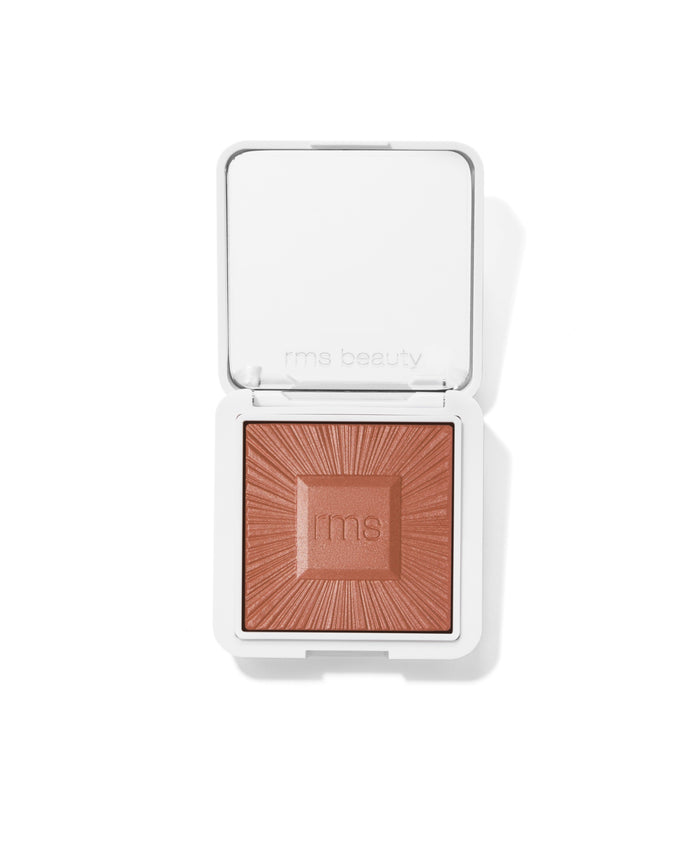 Compact powder makeup in warm brown shade with embossed sunburst design and "rms" logo on surface, in a white square case, ReDimension Hydra Bronzer.