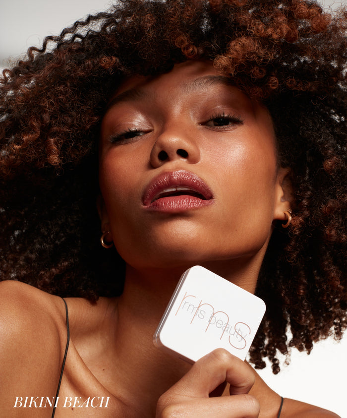 Close-up of a woman with glowing skin and natural makeup holding a compact of ReDimension Hydra Bronzer, highlighting clean beauty and skincare infused makeup.