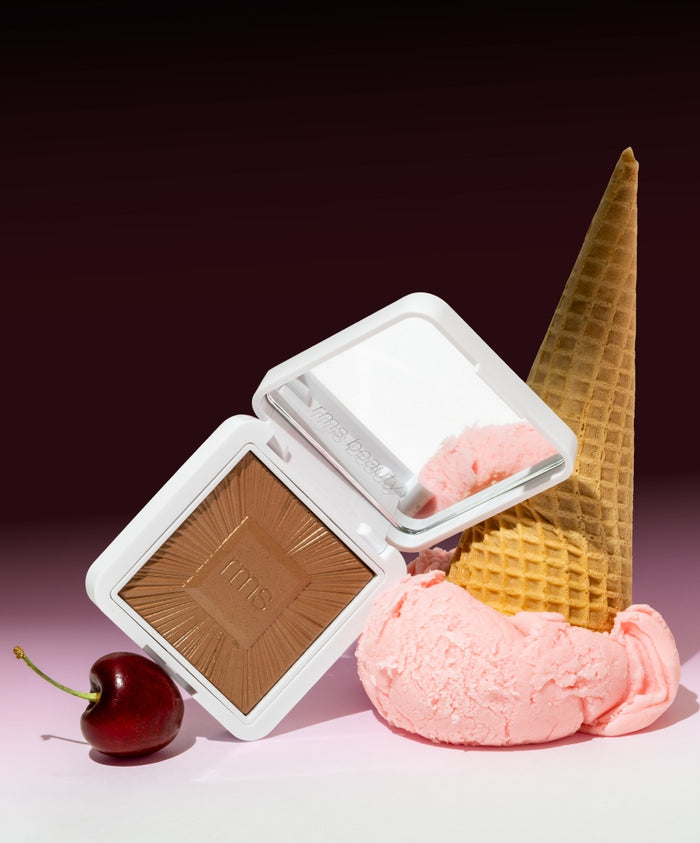 ReDimension Hydra Bronzer compact displayed next to a scoop of pink ice cream with a waffle cone and a cherry on a soft gradient background, highlighting clean beauty and natural ingredients.