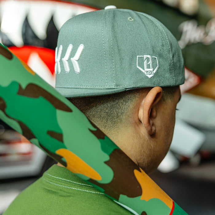 Olive green snapback hat with white embroidered baseball seam stitch design