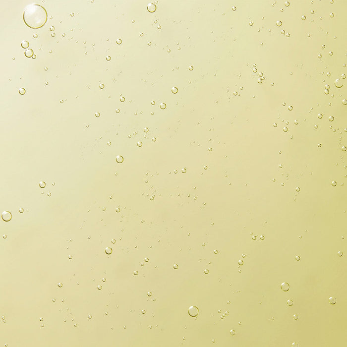 Close-up of a golden-yellow gel texture with small air bubbles, showing the smooth, cleansing consistency of Tropic’s Signature Hand Wash.