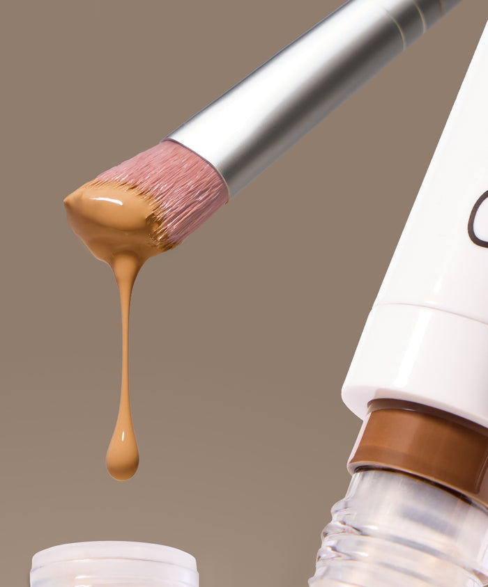 Close-up of the Skin2Skin Concealer Brush with natural beige concealer dripping from its soft bristles, highlighting smooth application and clean beauty makeup essentials.