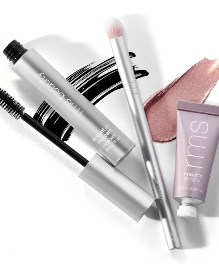 Skin2Skin Everything Eye Polish Brush with soft pink bristles placed beside RMS Beauty mascara wand and light mauve cream eyeshadow on white background highlighting clean beauty and sustainable packaging.
