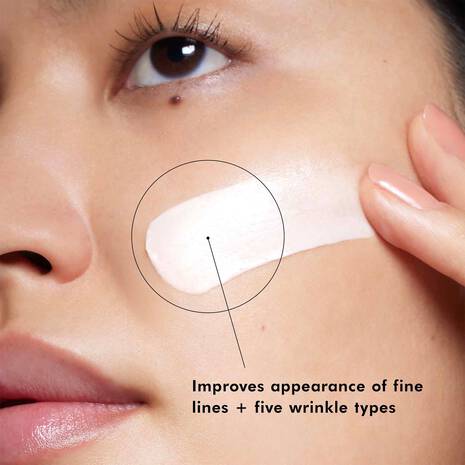 Woman applying SkinCeuticals A.G.E. Interrupter Advanced cream to cheek for fine lines and wrinkles