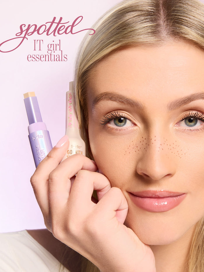 with holding tarte shape tape blur stick and go with the faux freckle stamp with text 'spotted IT girl essentials'