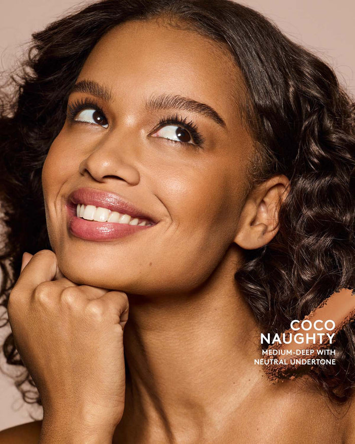 Medium-deep skin tone model wearing sun stalk'r bronzer in shade Coco Naughty.