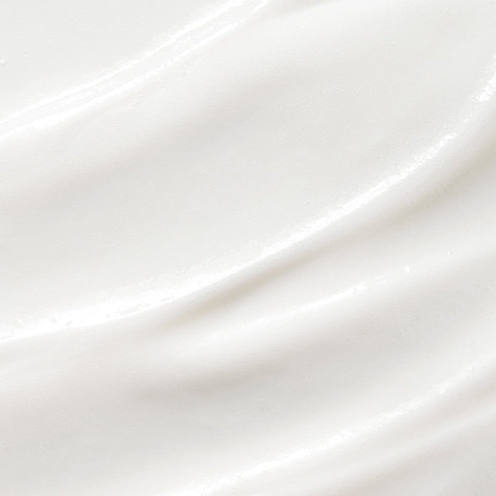 Close-up texture of smooth white cream with soft, glossy ridges, showing the rich consistency of a hydrating hand lotion.