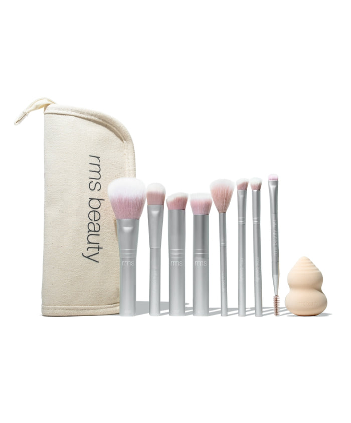 The Artist Toolkit featuring a set of nine makeup brushes with soft pink bristles, a beige blending sponge, and a matching natural fabric pouch with rms beauty branding.
