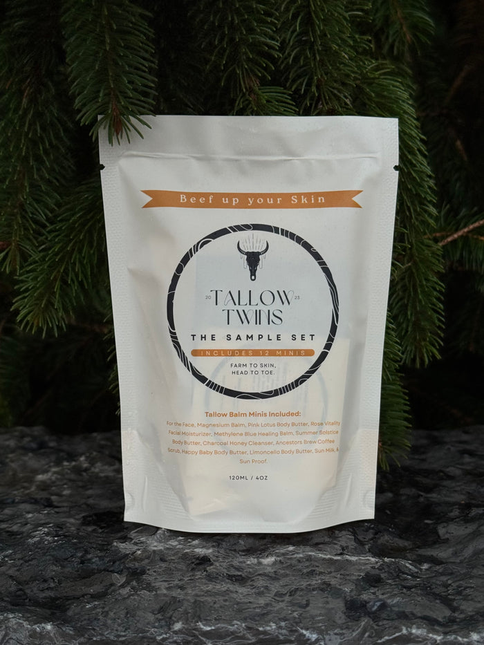 The Tallow Twins Sample Set pouch, containing twelve balm minis, against evergreen branches.