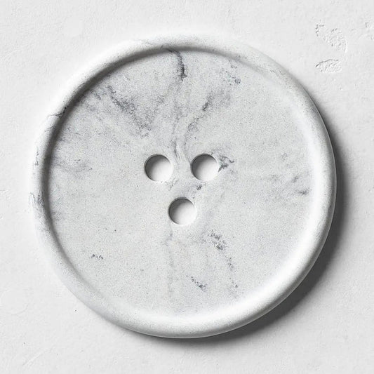 The UME - GREY MARBLE BOUTON ERODE SOAP DISH by UME STUDIO, featuring three holes in a triangle pattern, rests on a smooth matching gray surface.