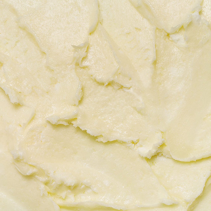 Close-up texture of Tropic Whipped Body Velvet, showing its rich, creamy, buttery consistency in a pale yellow shade that highlights its deeply nourishing formula.