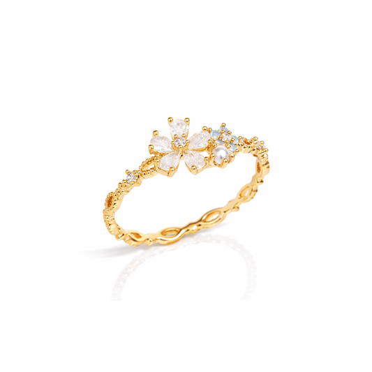 Gold-tone flower ring with white petals and small blue stone accents